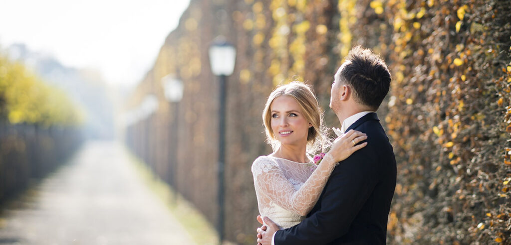 Ein Hochzeitsfotograf fängt ein stilvolles Brautpaar im Vintage-Stil vor einem Oldtimer ein.